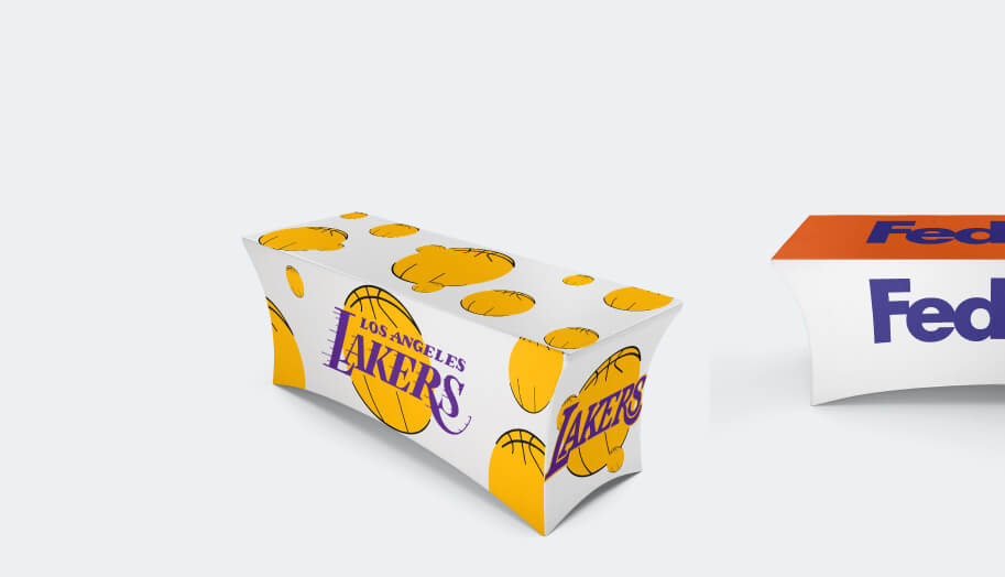 Two tables covered by personalized stretched tablecloths that display branding and logos of Lakers and Fedex.